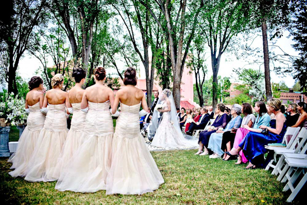 bridesmaids standing at the front of the ceremony in matching mermaid style light pink dresses watching the bride as she walks down the aisle - photo by New Mexico based wedding photographers Twin Lens